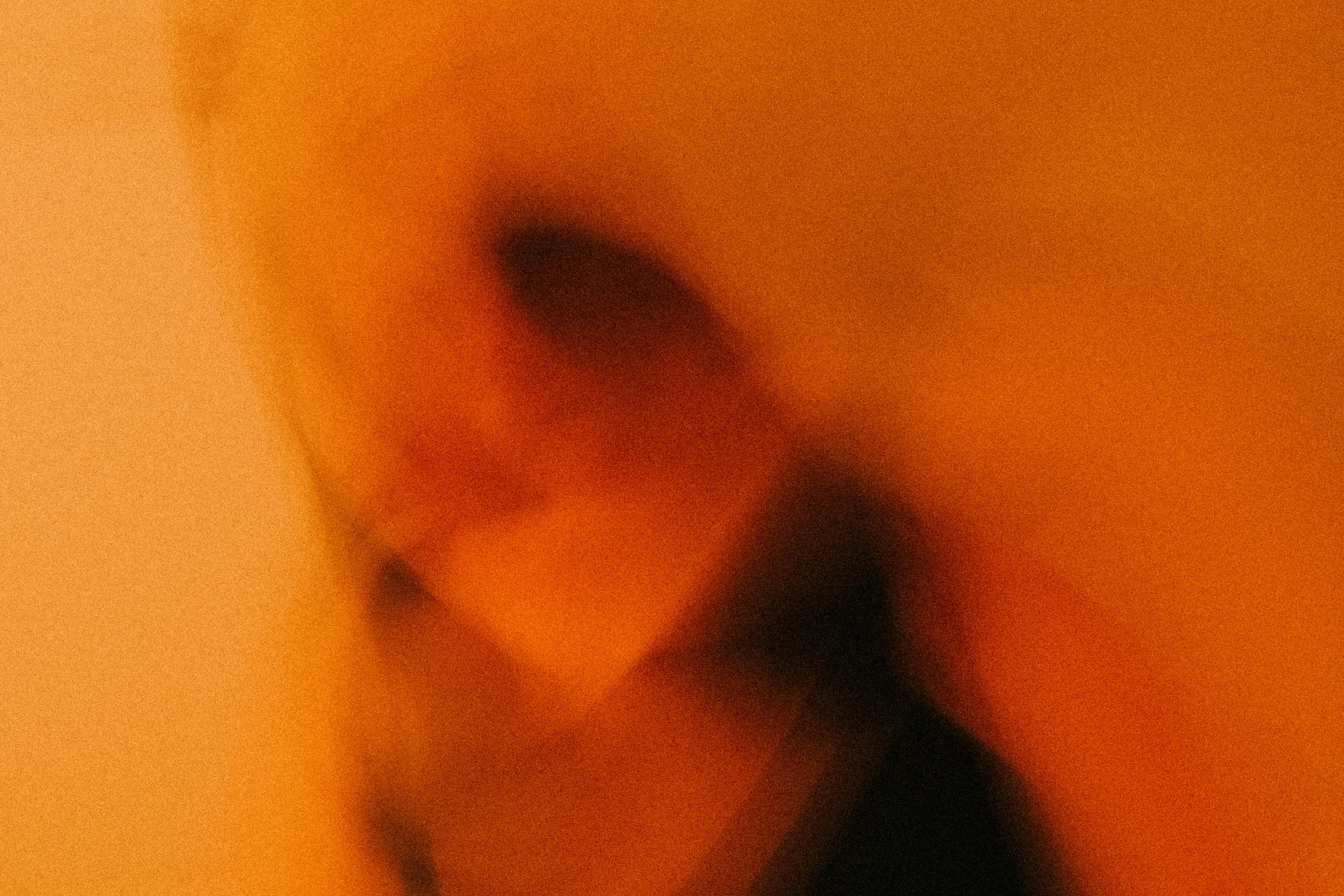 Abstract blurred portrait in warm orange tones with soft motion and grain